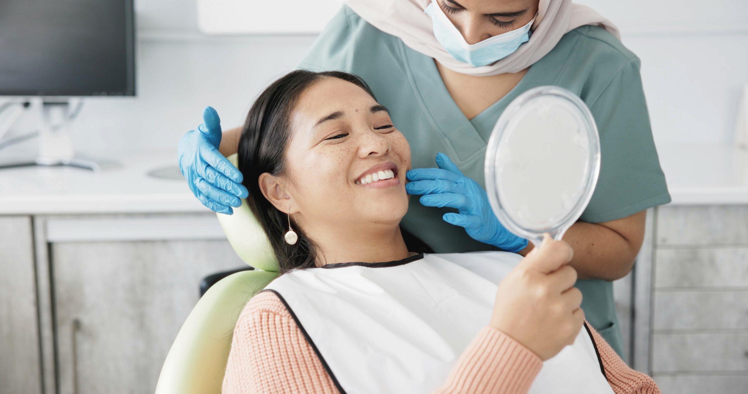 preventative-dentistry Patient smiling and examining teeth with a mirror during preventative dental care.
