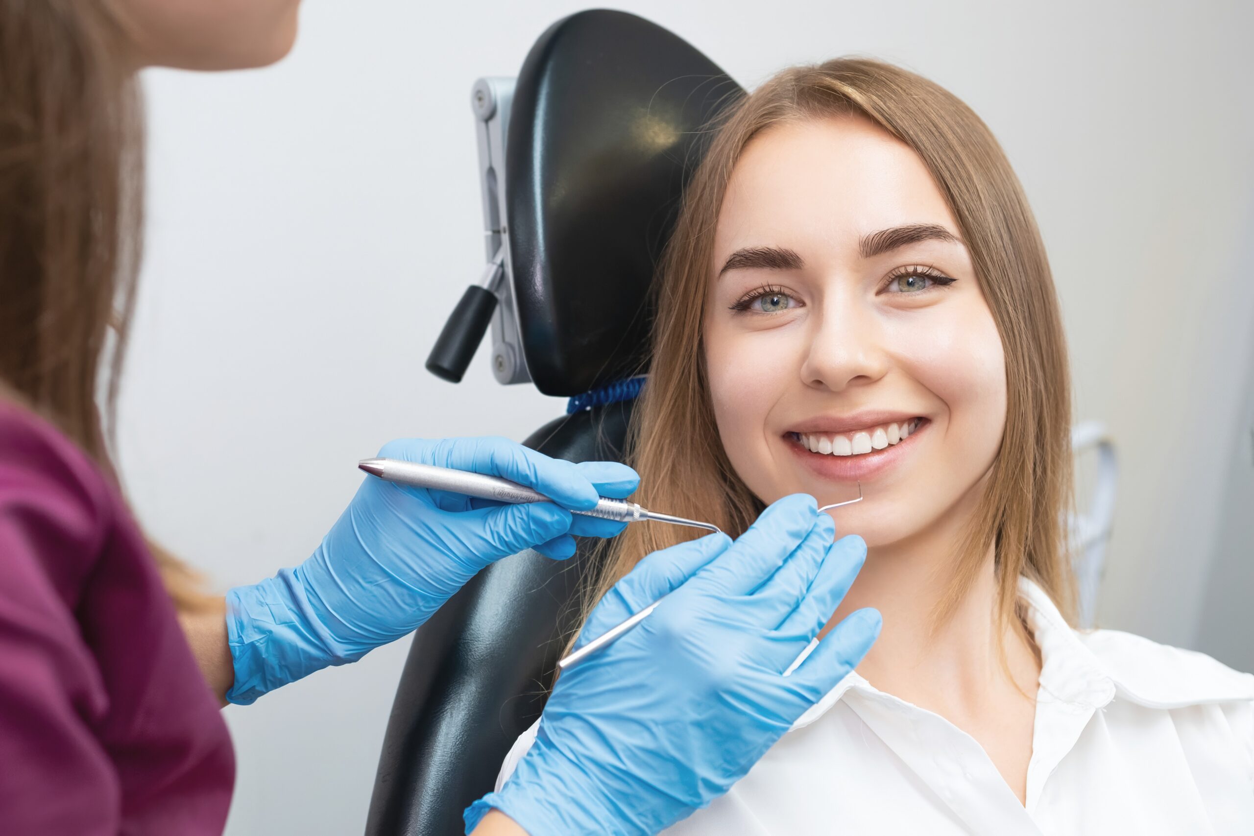 Smiling woman in dental chair receiving smile makeover consultation.