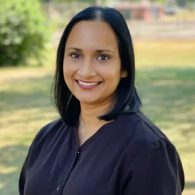 Dr. Swetha Madala, Grand Rapids dentist, smiling outdoors in a black blouse, showcasing her compassionate approach to oral health and expertise in general dentistry.