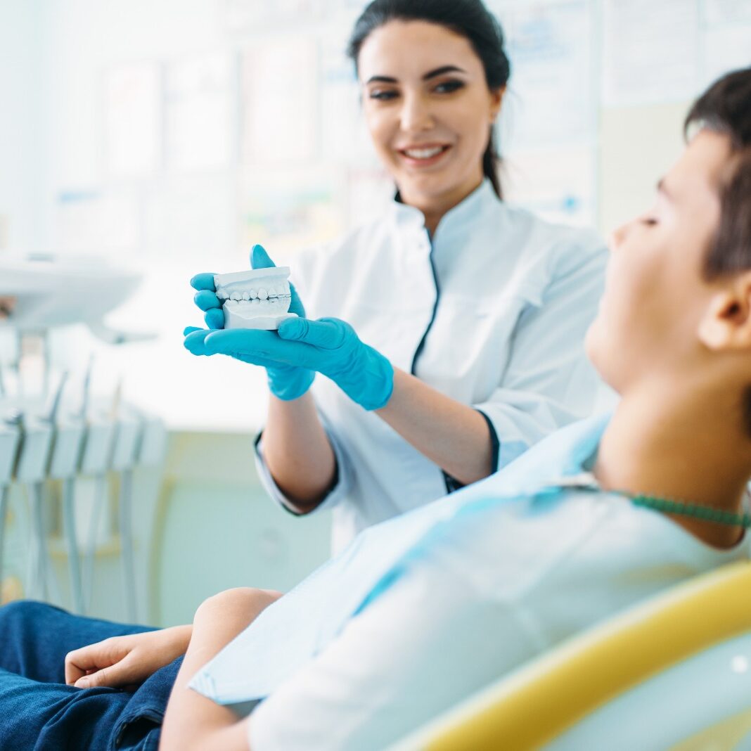 Dental professional demonstrating teeth model to patient in dental office, emphasizing patient-centered care at Midwest Family Dental Care in Portage.